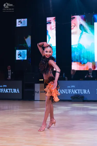 Dancesport competitor: Female dancer: black and orange Latin dress with long black fringe on the bodice