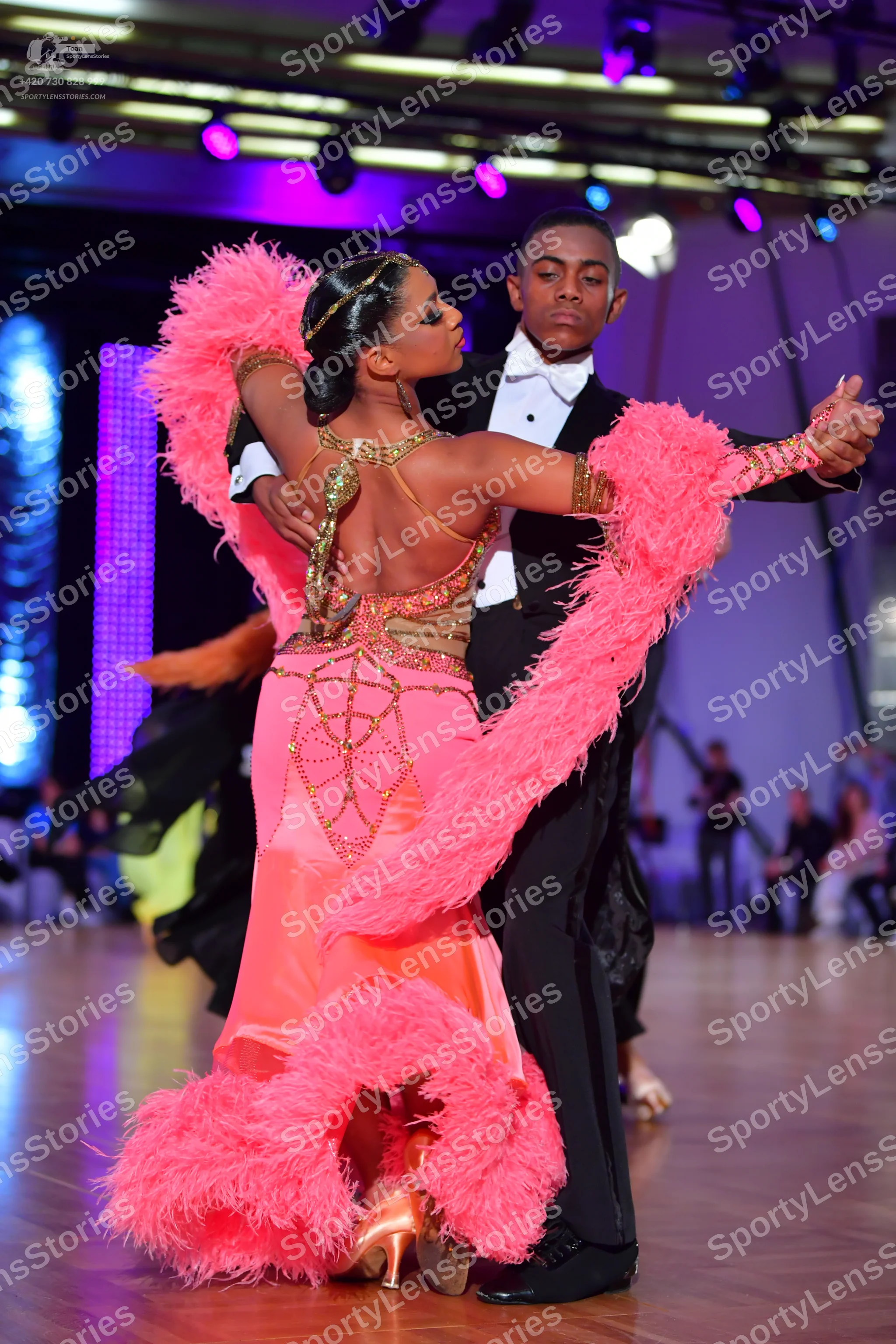 Dancesport competitor: Female dancer: pink Latin dress with large pink feather trim on the sleeves and