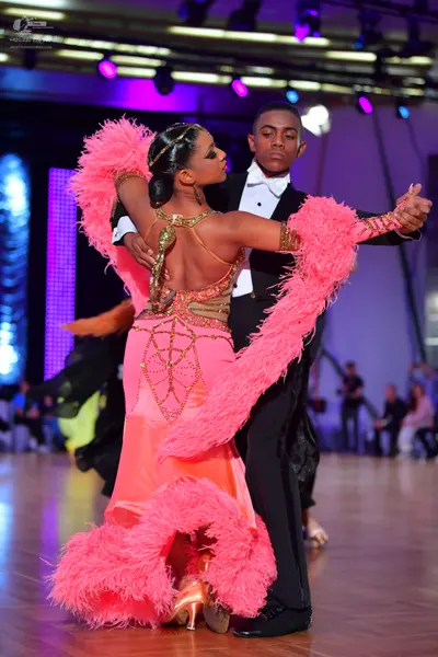 Dancesport competitor: Female dancer: pink Latin dress with large pink feather trim on the sleeves and 