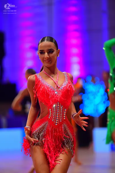 Dancesport competitor: Female dancer: red latin dress with fringe and rhinestones, wearing a necklace a