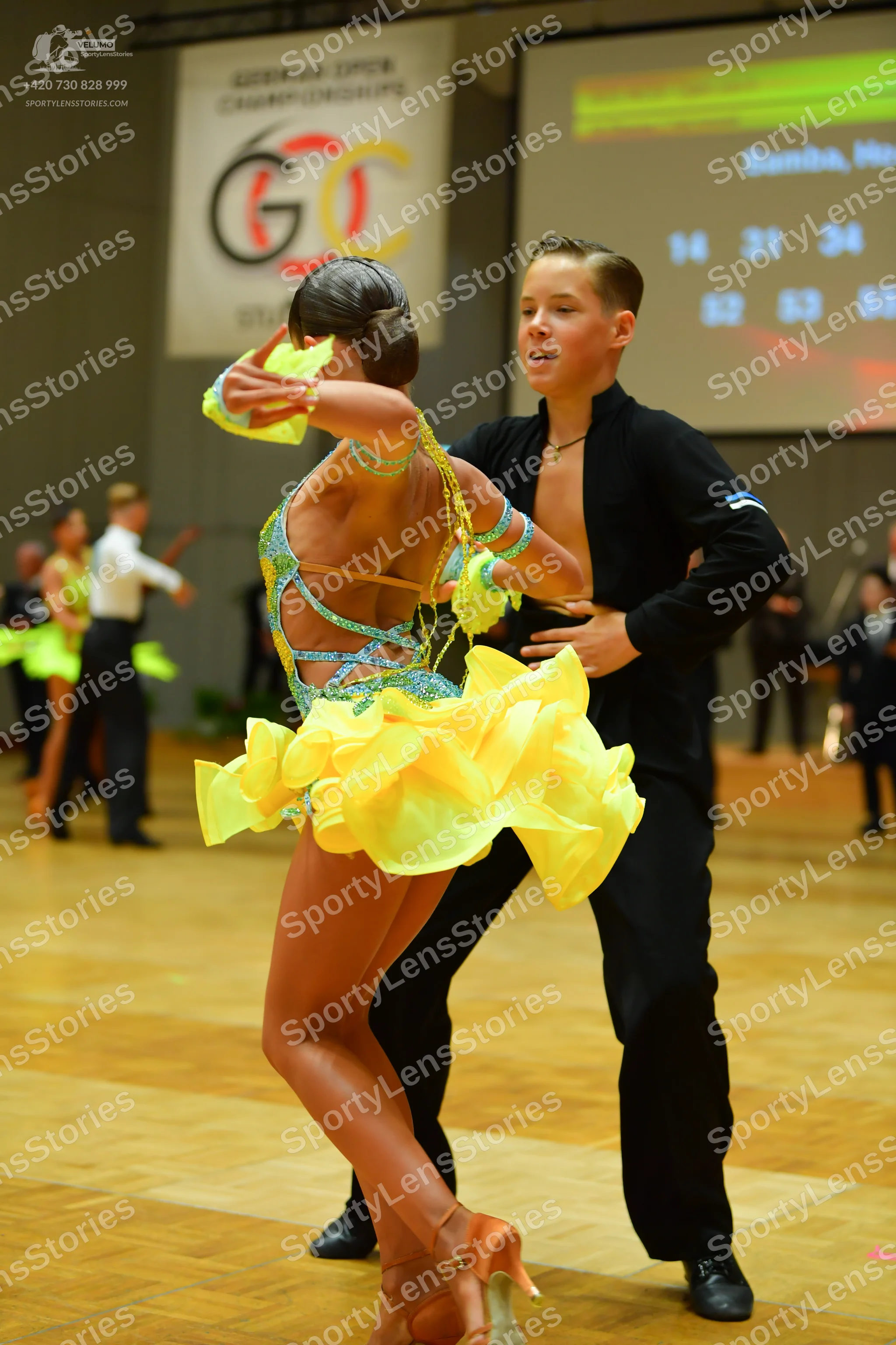 Dancesport competitor: Female dancer: bright yellow/lime green Latin dance dress with a sequined, multi