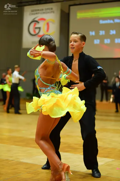 Dancesport competitor: Female dancer: bright yellow/lime green Latin dance dress with a sequined, multi