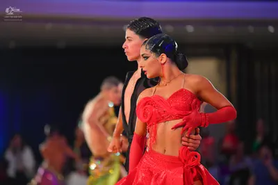 Dancesport competitor: Main female dancer: red Latin dress with an embellished bodice and long red glov