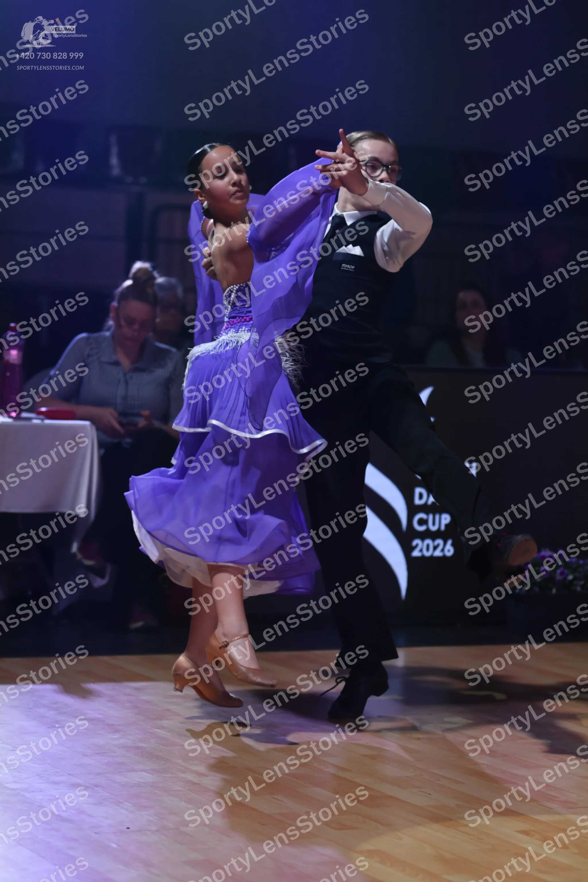 Dancesport competitor: Female dancer: purple ballroom dress with a flowing, layered skirt and a decorat