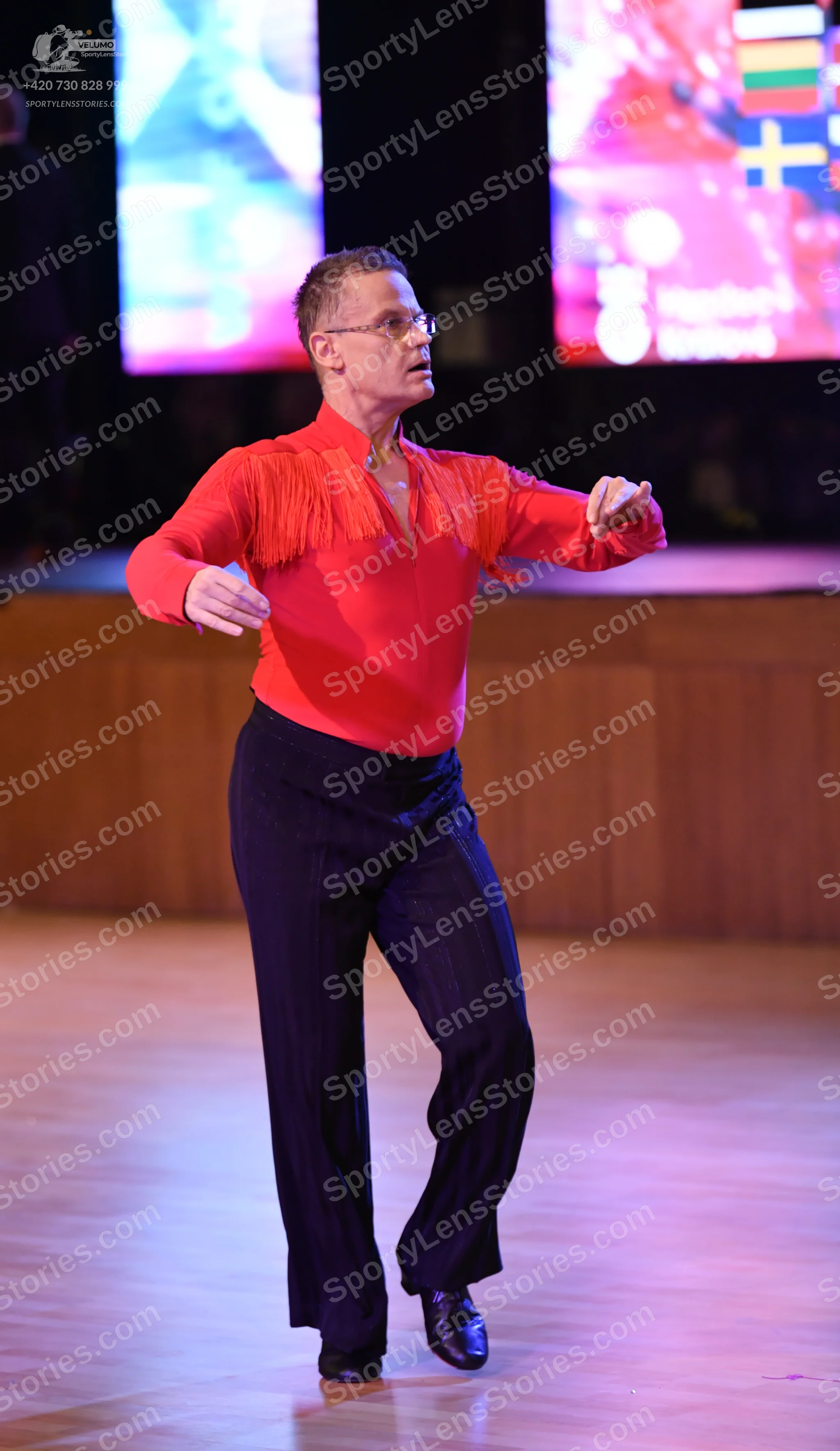 Dancesport competitor: Male dancer: orange long-sleeved shirt with fringe detailing on the chest, black