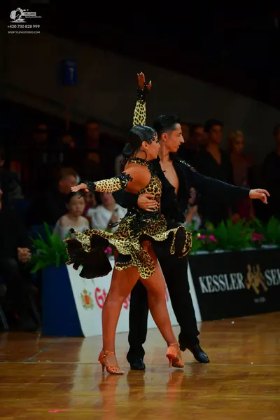 Dancesport competitor: Female dancer: leopard print Latin dress with black embellishments, a flared ski