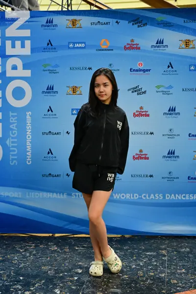 Dancesport competitor: Female dancer: black zip-up jacket with white "wang" lettering, black shorts wit