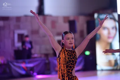 Dancesport competitor: Female dancer: black latin dress with an orange honeycomb pattern and long orang