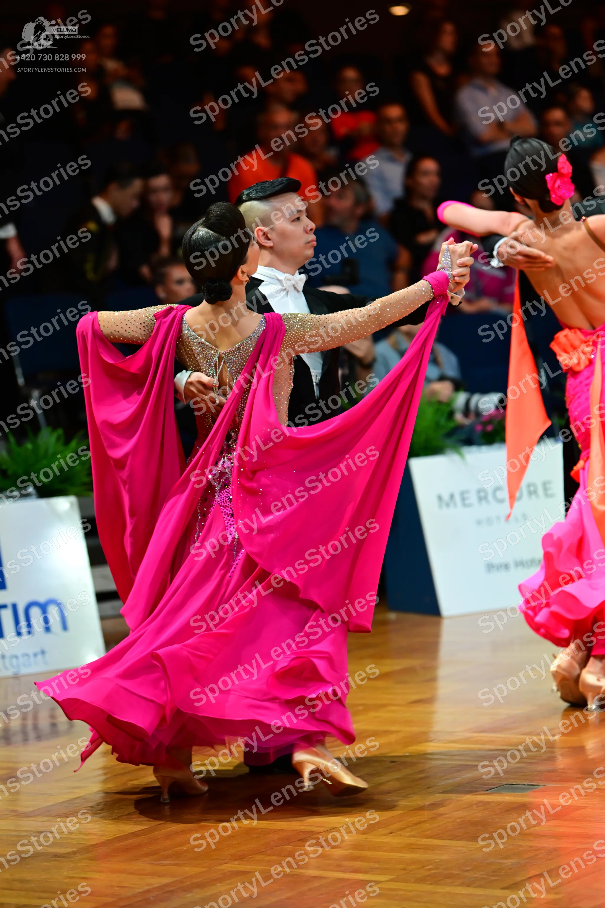 Dancesport competitor: Female dancer: pink ballgown with a large, flowing skirt and sheer sleeves with