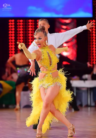 Dancesport competitor: Female dancer: yellow latin dress with sequins and feather fringe, long yellow g