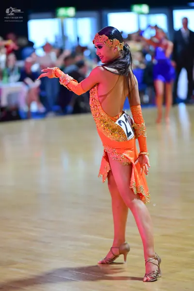 Dancesport competitor #21: Female dancer in foreground: orange latin dress with sequins and long sleeves