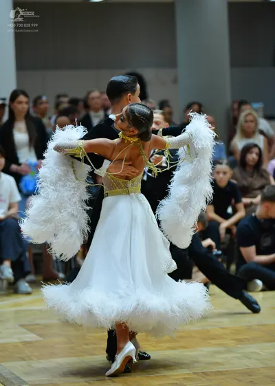Dancesport competitor: Female dancer: white ballroom dress with a voluminous feather-trimmed skirt and 