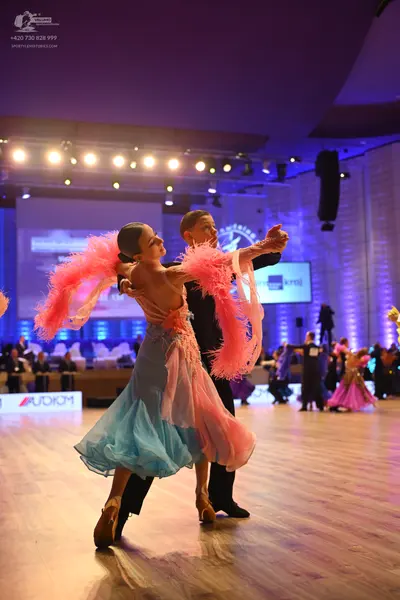 Dancesport competitor: Female dancer: light blue tulle ballgown with voluminous skirt and large pink fe