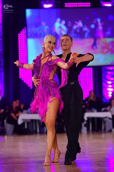 Dancesport competitor: Female dancer: magenta latin dress with fringe and matching arm cuffs