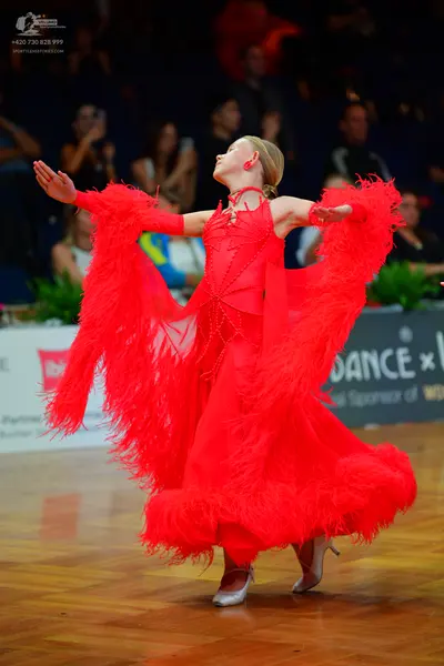 Dancesport competitor: Female dancer: red dance dress with large, feathery red fringe on the sleeves an