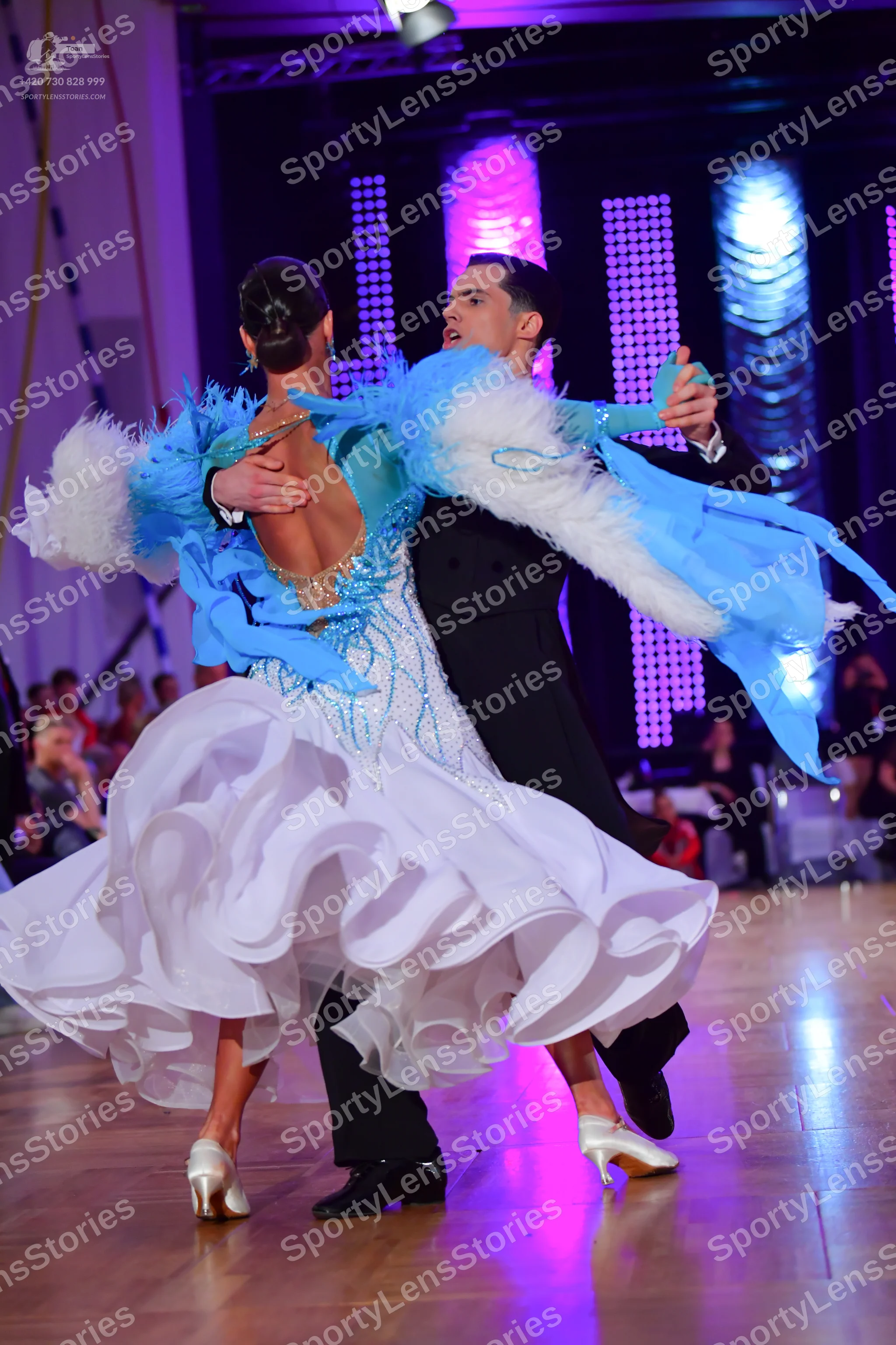 Dancesport competitor: Female dancer: white ballgown with light blue feathery accents on the shoulders 