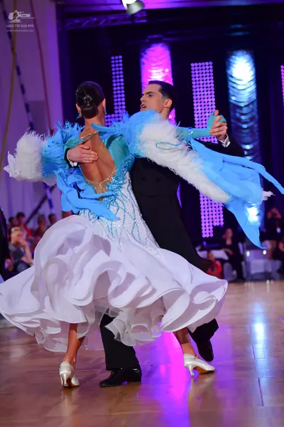 Dancesport competitor: Female dancer: white ballgown with light blue feathery accents on the shoulders 