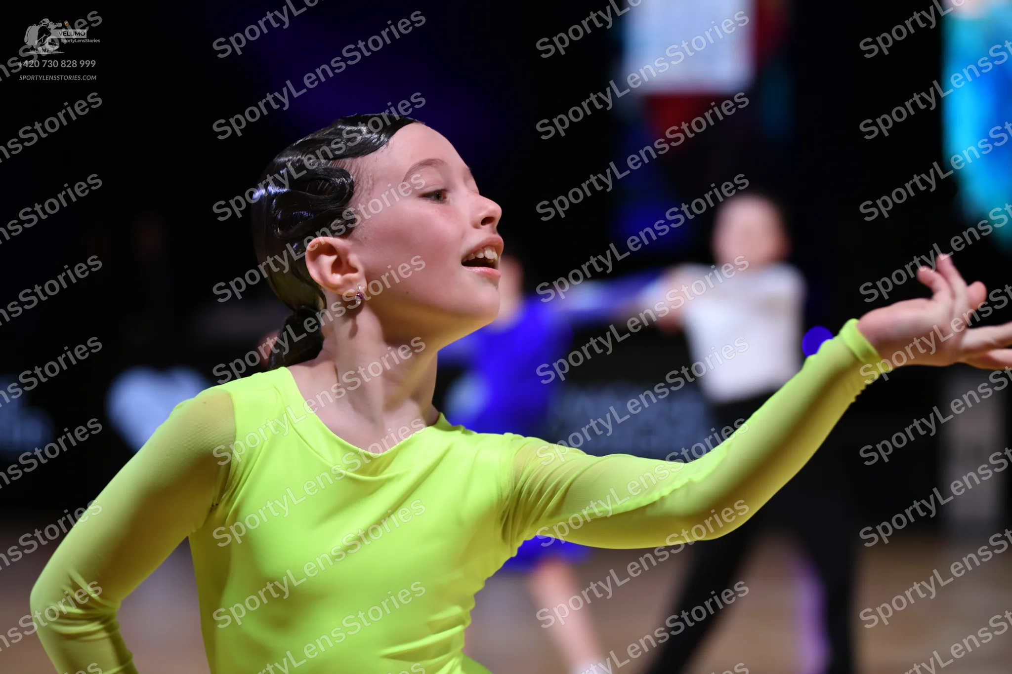 Dancesport competitor: Female dancer in foreground: lime green long-sleeved latin dress made of smooth,