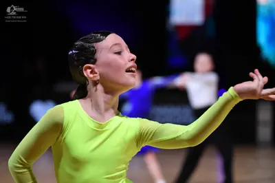 Dancesport competitor: Female dancer in foreground: lime green long-sleeved latin dress made of smooth,