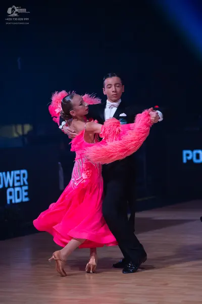 Dancesport competitor: Female dancer: bright pink latin dress with large pink feather details and sequi