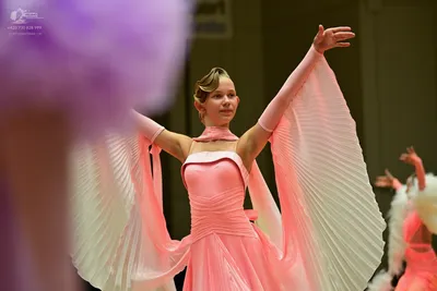 Dancesport competitor: ** Female: Light pink, flowing pleated dress with wide, gathered sleeves