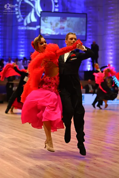 Dancesport competitor: Female dancer: bright pink Latin dance dress with a voluminous, textured skirt a