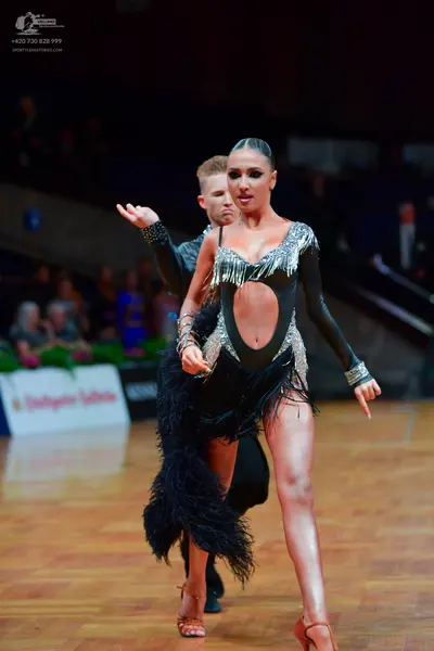 Dancesport competitor: Male dancer: black long-sleeved top with sequined cuffs and black trousers