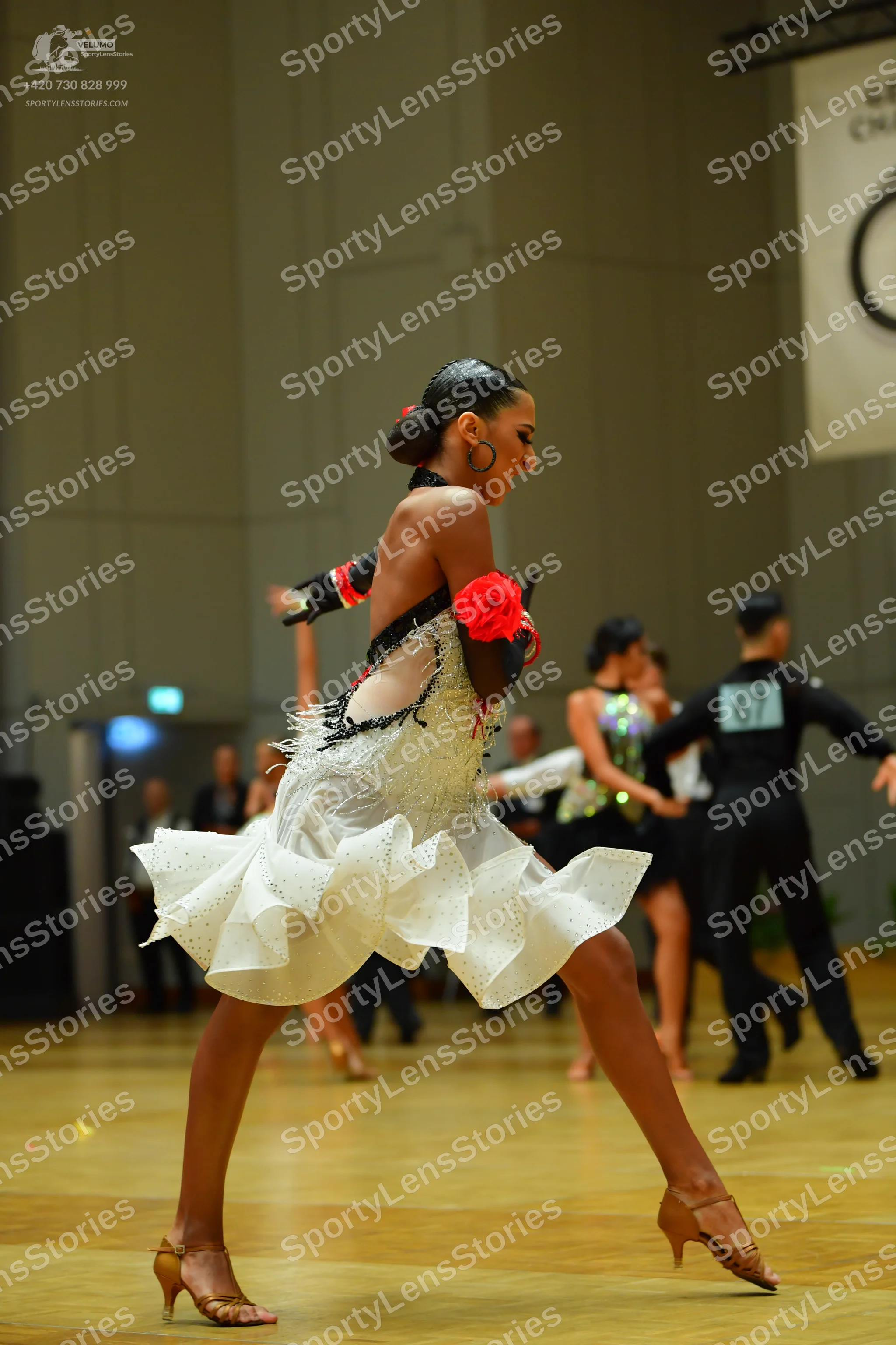 Dancesport competitor: Female dancer (foreground): black and white Latin dress with a white ruffled ski