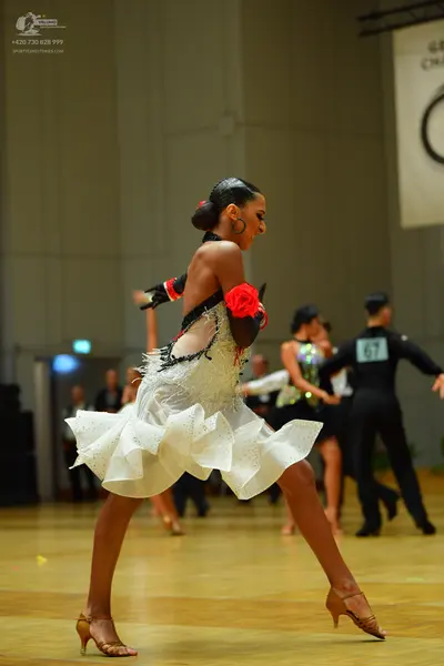 Dancesport competitor: Female dancer (foreground): black and white Latin dress with a white ruffled ski