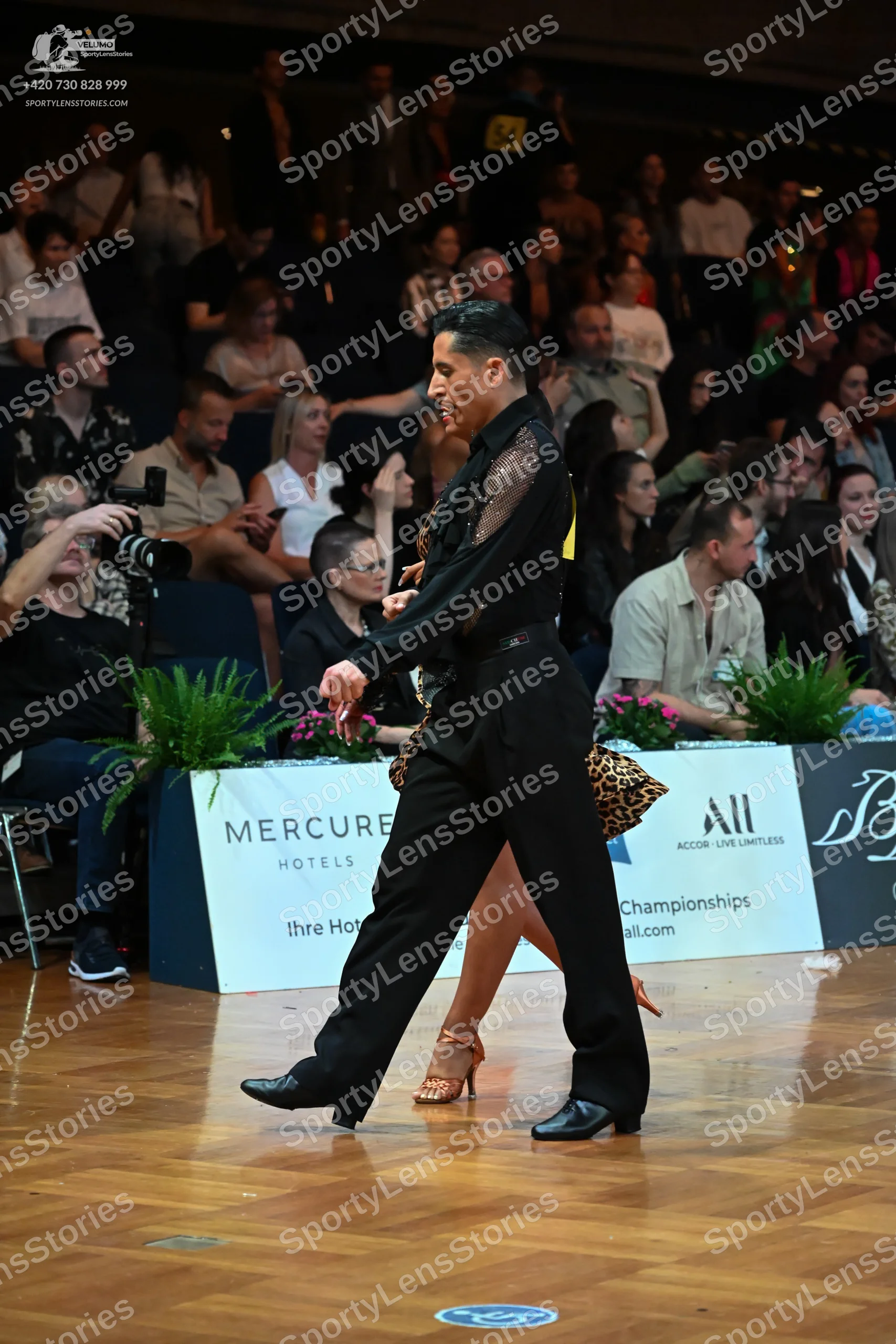 Dancesport competitor: Male dancer: black long-sleeved shirt with black lace or mesh detailing on the c