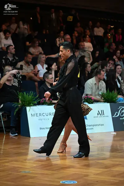 Dancesport competitor: Male dancer: black long-sleeved shirt with black lace or mesh detailing on the c