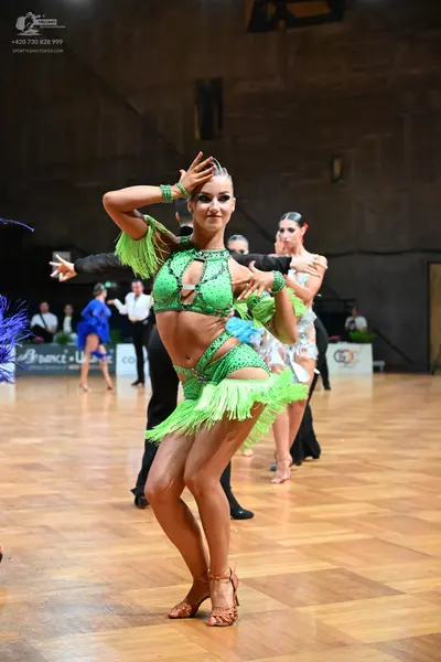 Dancesport competitor: Primary female dancer: lime green Latin dance costume with sequins, cutouts, and