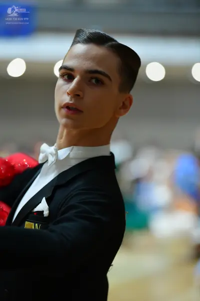 Dancesport competitor: Male dancer: black suit with a white shirt, white bowtie, and white pocket squar