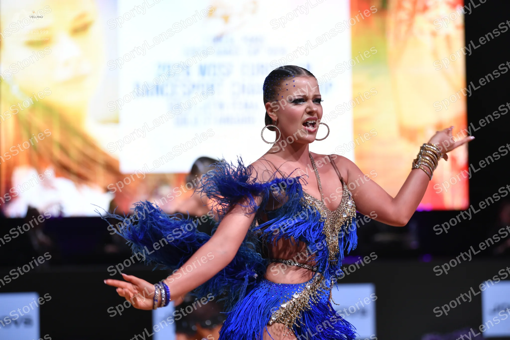Dancesport competitor: Female dancer: blue latin dress with blue fringe and gold sequin/beaded details,