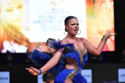 Dancesport competitor: Female dancer: blue latin dress with blue fringe and gold sequin/beaded details,