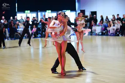 Dancesport competitor: Central female dancer: white/silver sequined Latin dance costume with sheer fabr