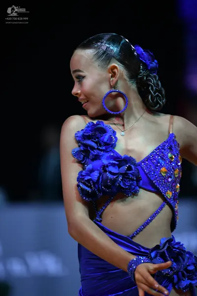 Dancesport competitor: Female dancer: blue Latin dress with satin-like fabric, featuring large 3D fabri