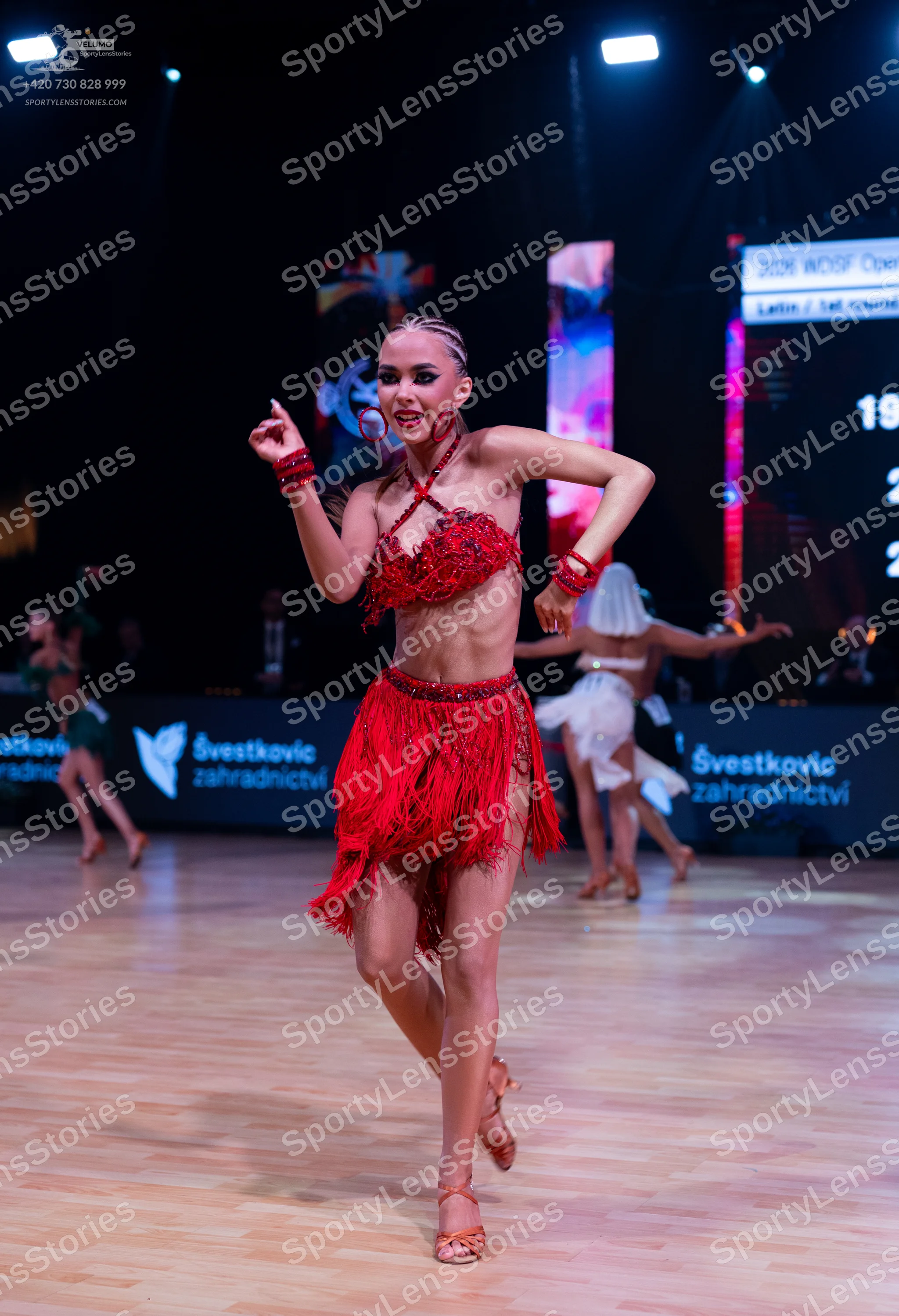 Dancesport competitor: Main female dancer: red latin dress with lace bodice, fringe skirt, and red wris