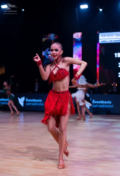 Dancesport competitor: Main female dancer: red latin dress with lace bodice, fringe skirt, and red wris