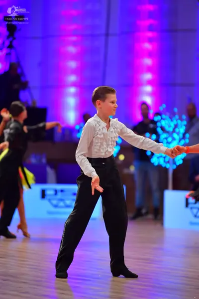 Dancesport competitor: Central dancer: white long-sleeved shirt with ruffles down the front and black t