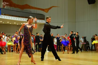 Dancesport competitor: Main female dancer: dark purple/black latin dress with heavy sequins and multi-c
