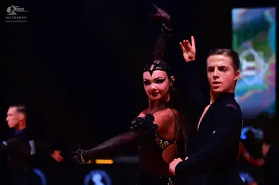 Dancesport competitor: Female dancer: dark (black or dark brown) latin dance costume with sheer mesh sl