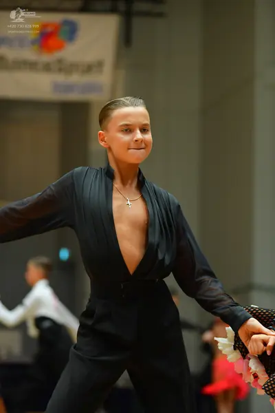 Dancesport competitor: Female dancer in foreground: black long-sleeved bodysuit or jumpsuit with a deep