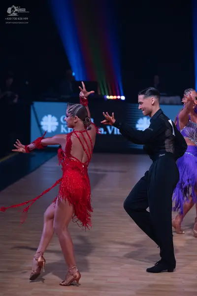 Dancesport competitor: Female dancer: red latin dress with long fringe and matching wristbands