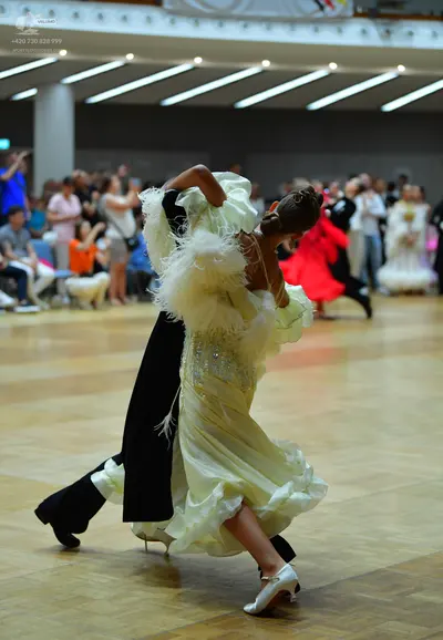 Dancesport competitor: Female dancer in foreground: voluminous, pale yellow/cream-colored ballgown with
