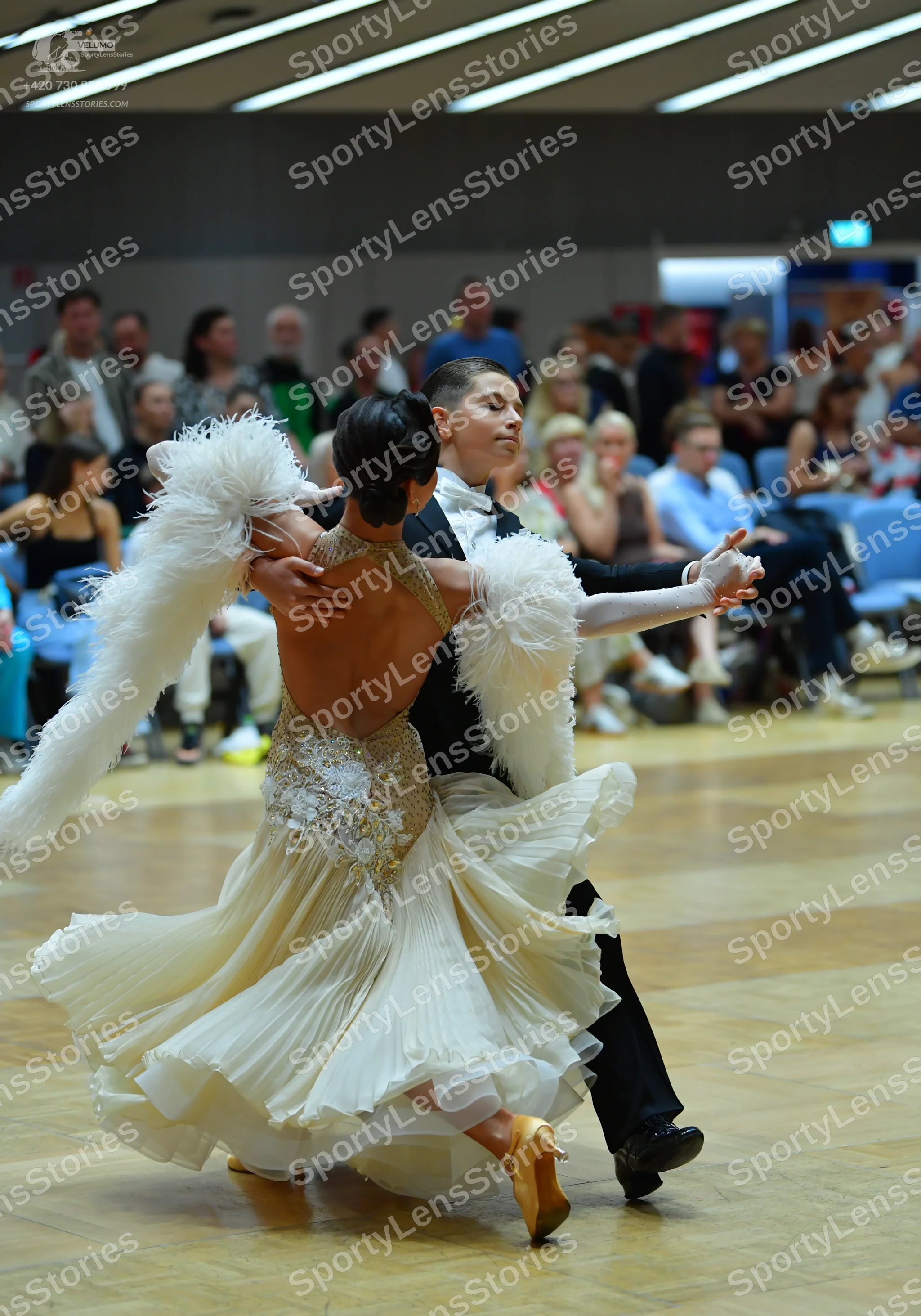 Dancesport competitor: Female dancer: cream-colored ballroom dress with a sequined bodice, a multi-laye
