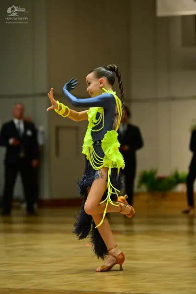 Dancesport competitor: Female dancer: dark blue Latin dance costume with bright neon yellow fringe and 