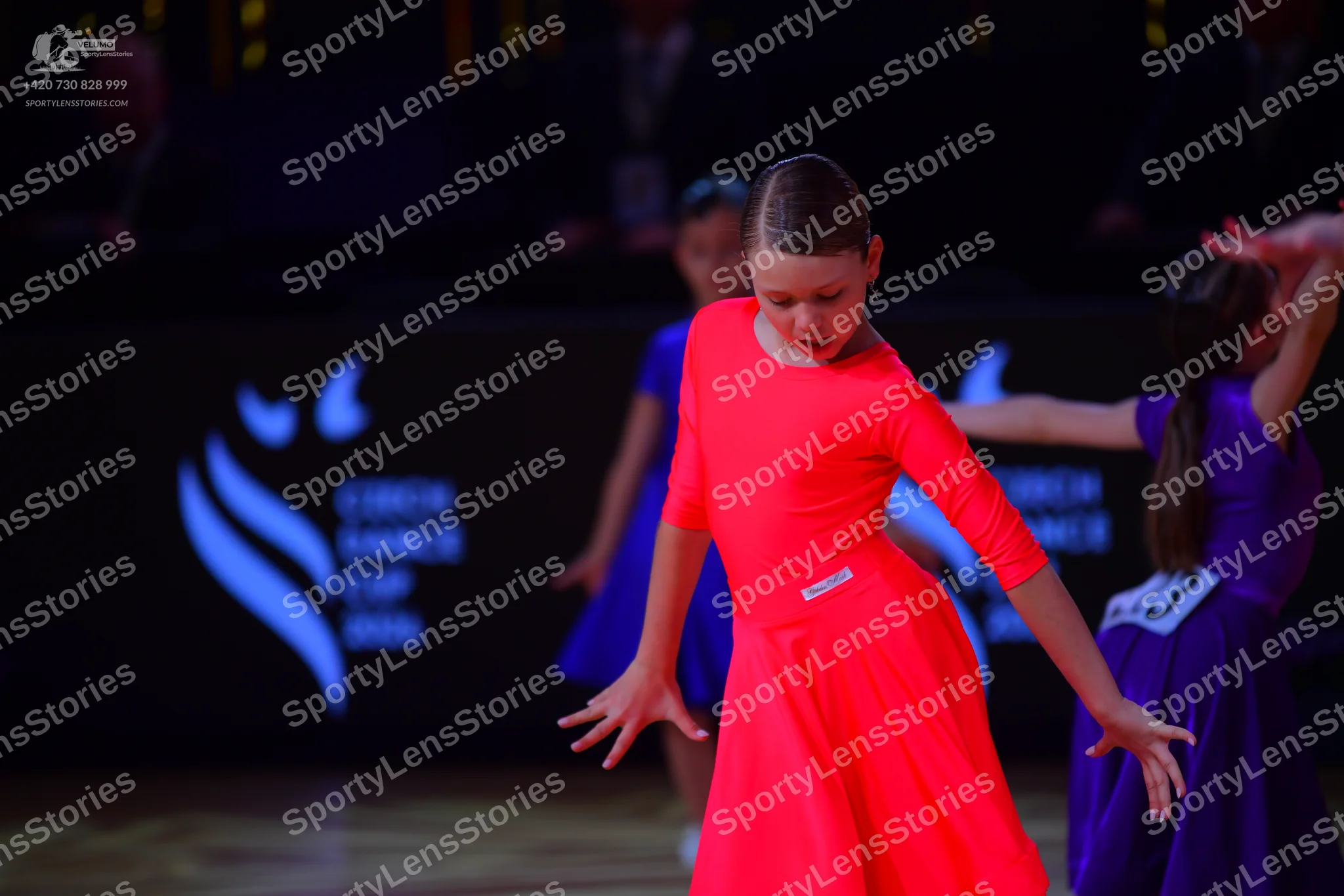 Dancesport competitor: Dancer 1: bright orange long-sleeved Latin dress with smooth fabric