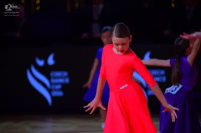 Dancesport competitor: Dancer 1: bright orange long-sleeved Latin dress with smooth fabric
