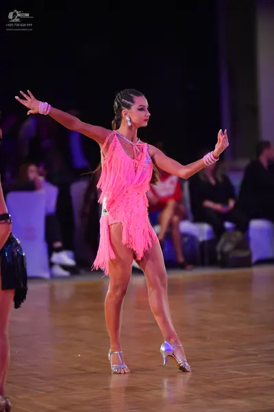 Dancesport competitor: Female dancer (center): pink Latin dress with long fringe, silver metallic dance